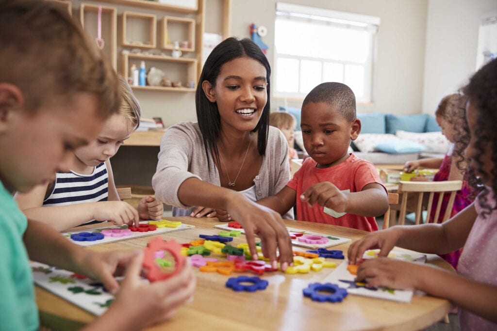 Photo of a teacher playing with preschoolers.
