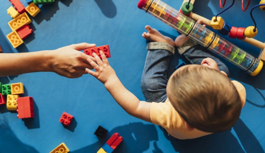 Boy one or two year old playing blocks with adult